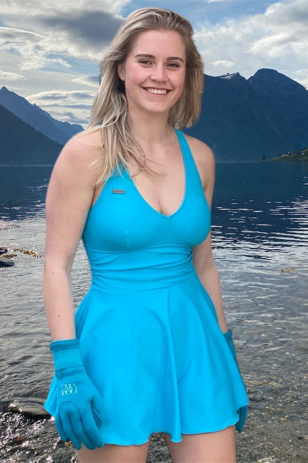 dame som smiler ved en fjord i Norge som har på seg badekjole og neopren hansker