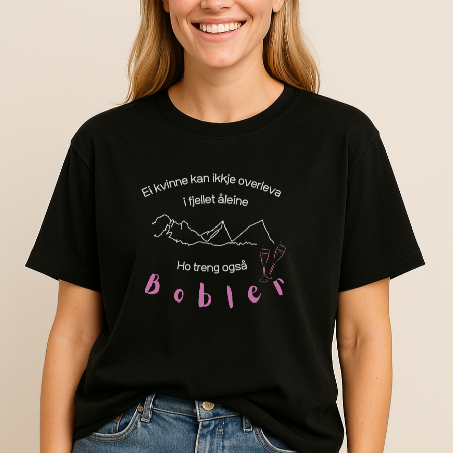 Ei dame med svart t-skjorte med prosecco design med trykk av bobler og fjell. Ei kvinne kan ikkje overleva i fjellet åleine, ho treng også bobler